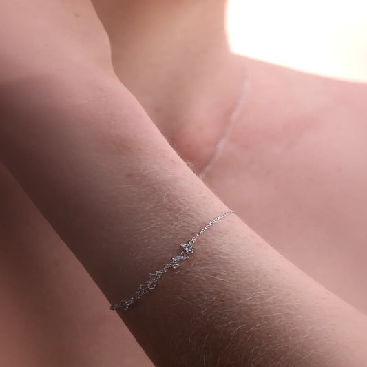 Close-up of a delicate multi-stone bracelet from the Reflections Collection in sterling silver, elegantly draping around a woman's wrist. The fine chain and shimmering stones catch the light, creating a soft, radiant glow against her skin.