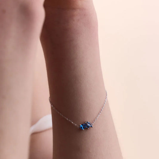 Elegant sterling silver bracelet with a trio of radiant blue topaz gemstones on a fine chain.