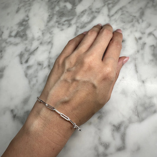 Sterling silver bracelet with sleek oblong links showcased on a wrist. Modern minimalist design, adjustable fit, and reflective surface perfect for casual or formal wear.