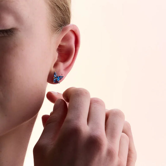 Model wearing vibrant sterling silver earrings featuring marquise-cut blue topaz stones in an elegant floral design.