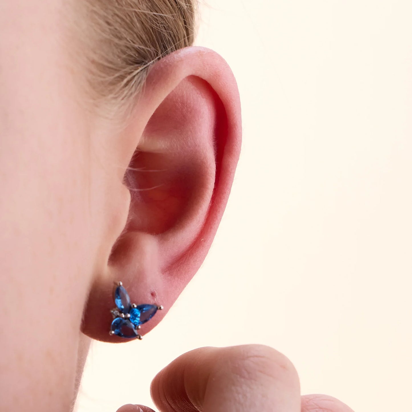 Close-up of sterling silver floral earrings with dazzling blue topaz gemstones showcasing their brilliant sparkle.