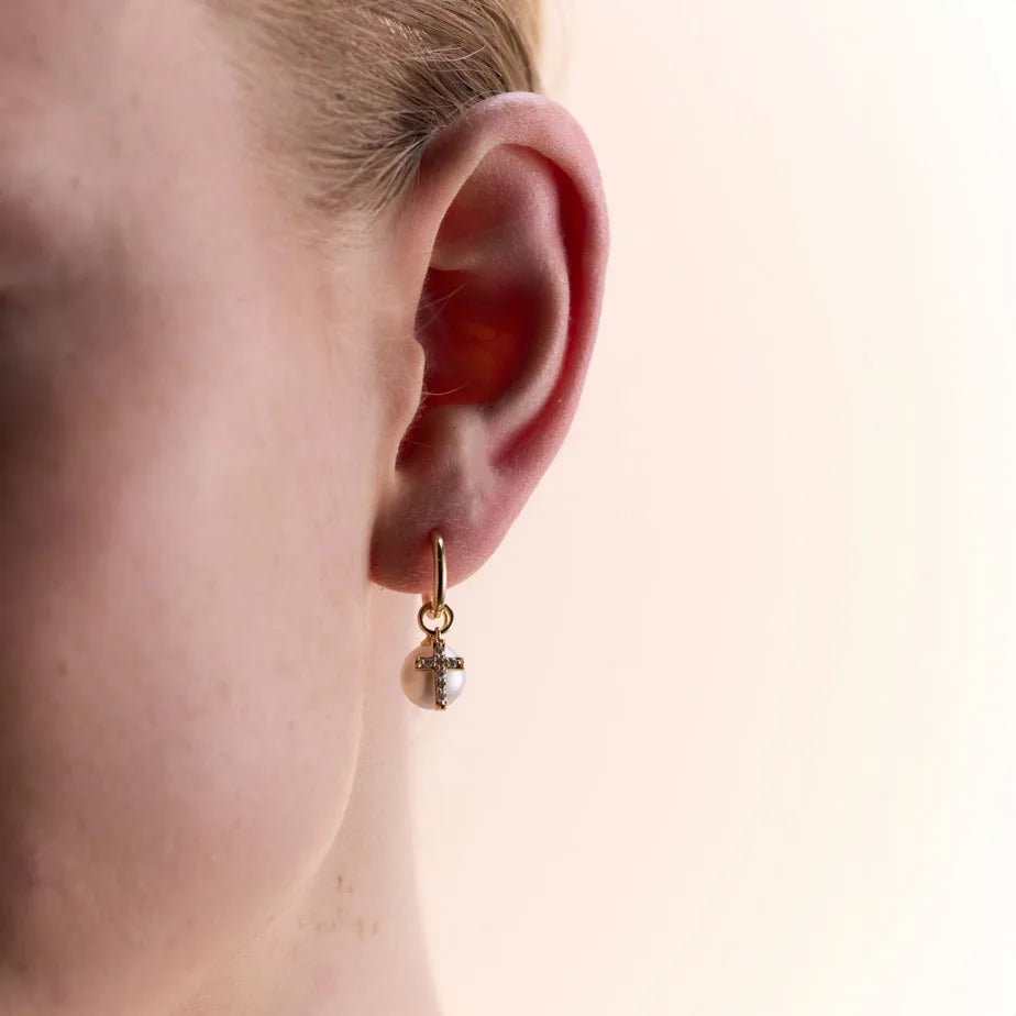 Model wearing 9k yellow gold hoop earrings featuring detachable diamond-studded cross charms, showcasing the refined design and comfortable fit.