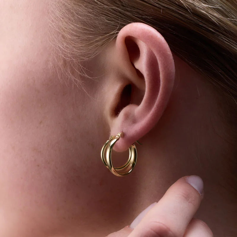 Side view of yellow gold plated round tube hoop earrings worn, highlighting their smooth, polished finish.