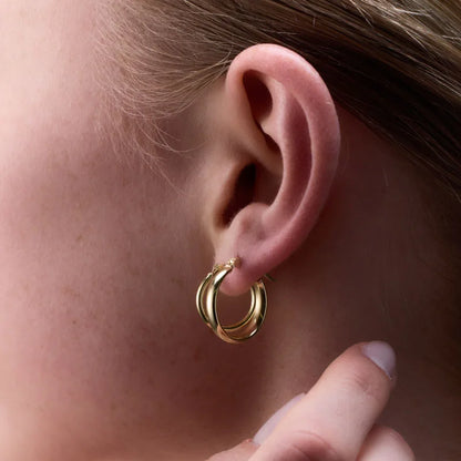 Side view of yellow gold plated round tube hoop earrings worn, highlighting their smooth, polished finish.