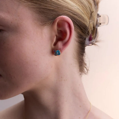 Side profile of a woman wearing sparkling yellow gold-plated earrings with blue topaz and amethyst, highlighting their timeless elegance.