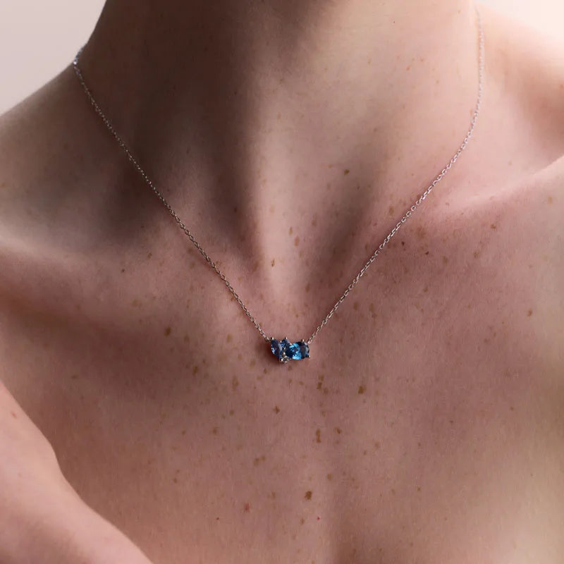 Close-up of a sterling silver necklace with a striking blue topaz centerpiece, elegantly crafted to complement both casual and formal outfits.