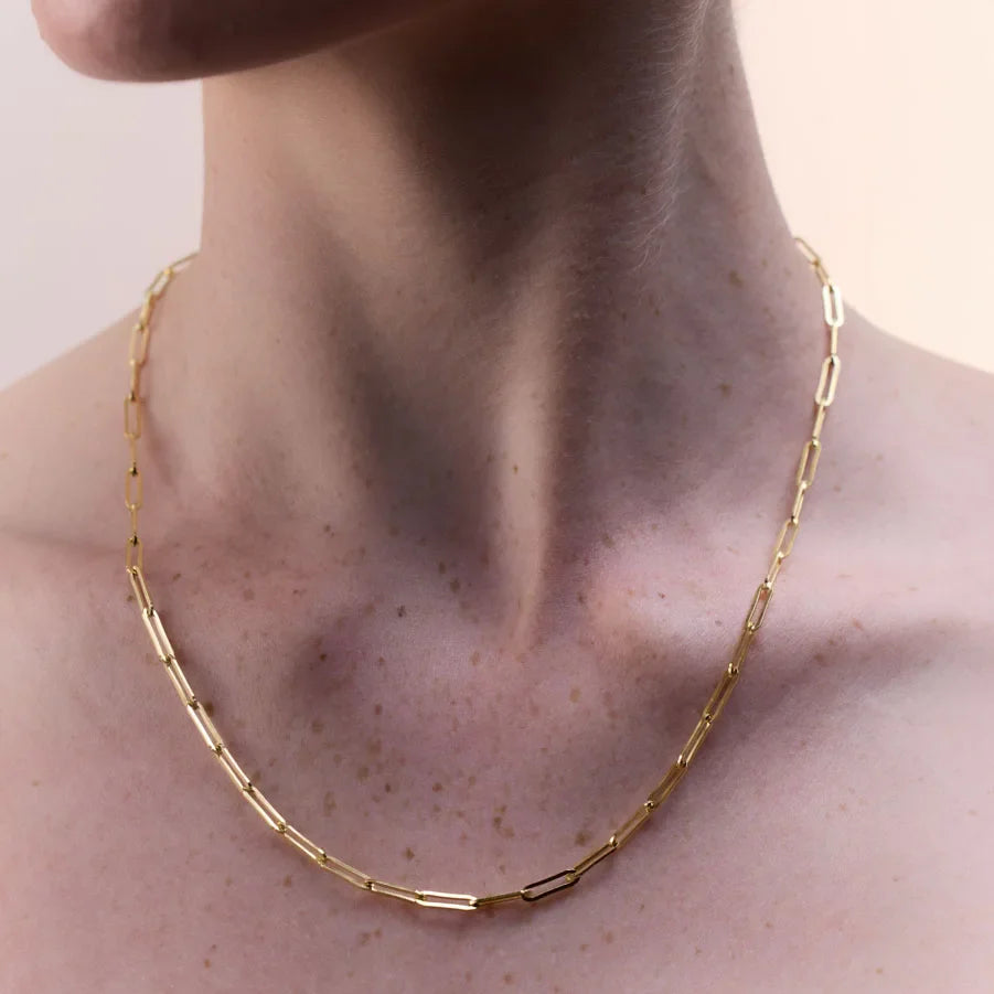 Elegant gold-plated oblong link chain necklace resting gracefully on a woman's neck, showcasing minimalist sophistication and versatile style, perfect for layering or wearing solo as a statement piece.