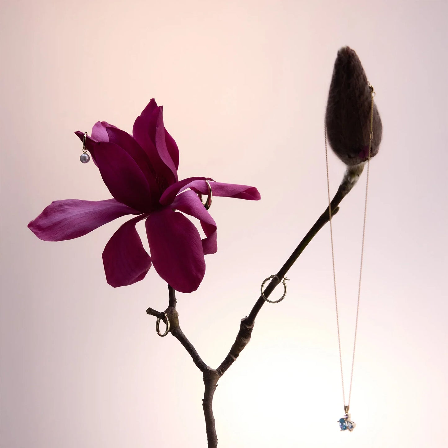 Elegant yellow gold-plated necklace with a centerpiece of blue topaz, amethyst, and cubic zirconia stones, styled with a magenta flower.