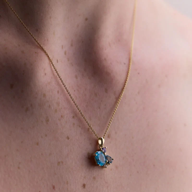 Close-up of a gold-plated necklace with a colourful gemstone cluster, featuring a London blue topaz and a sparkling cubic zirconia.