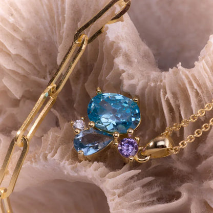 Side angle view of a gold-plated necklace with a dazzling blue topaz, amethyst, and cubic zirconia centerpiece, perfect for gifting or personal wear.