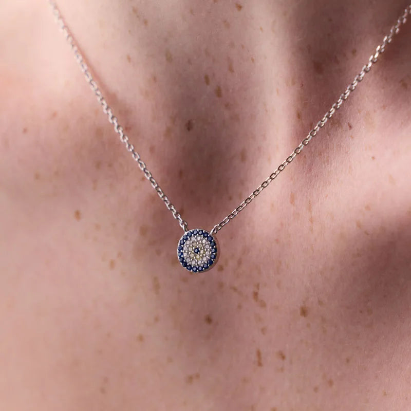 Elegant sterling silver evil eye pendant necklace featuring sparkling blue and white cubic zirconia stones on a rhodium-plated chain.